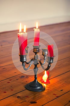Tin candleholder with bruning red candles and dripping wax on wooden floor photo