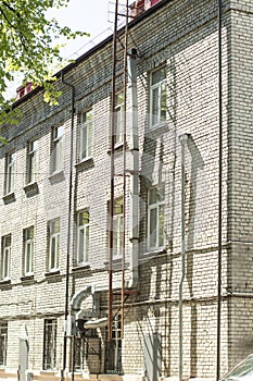 Tin exhaust system hanging on the wall of a brick building