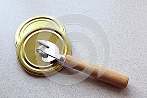 Tin lids with a bottle opener on a gray background, space for text