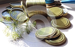 Tin lids for canning with a branch of dill on the background of the seaming machine, close-up