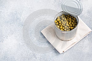 Tin open jar with canned peas on a gray concrete background. copy space