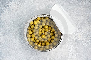 Tin open jar with canned peas on a gray concrete background. copy space