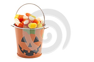 A Tin Pumpkin Jack O Lantern Bucket FIlled with Candy Corn on a White Background