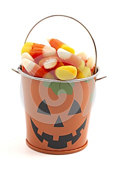 A Tin Pumpkin Jack O Lantern Bucket FIlled with Candy Corn on a White Background