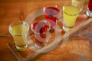 Tincture alcoholic in small shot glasses. Natural fruit alcohol drinks, shots served on a wooden table