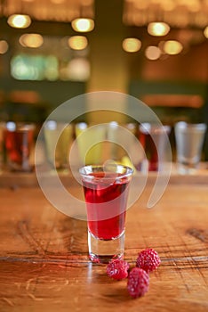 Tincture alcoholic in small shot glasses. Natural fruit alcohol drinks, shots served on a wooden table