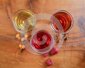 Tincture alcoholic in small shot glasses. Natural fruit alcohol drinks, shots served on a wooden table