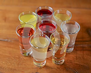 Tincture alcoholic in small shot glasses. Natural fruit alcohol drinks, shots served on a wooden table