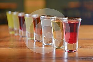 Tincture alcoholic in small shot glasses. Natural fruit alcohol drinks, shots served on a wooden table.