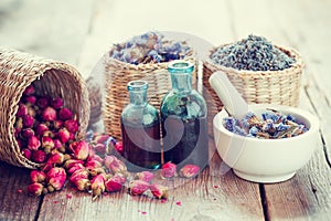 Tincture, basket with rose buds, lavender and dried flowers in mortar photo