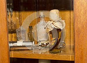 Tincture in a glass bottle with seahorses inside and an old medical syringe on a shelf