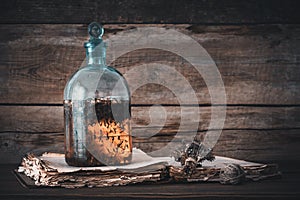 Tincture or potion bottle, old book and bunch of dry healthy herbs.