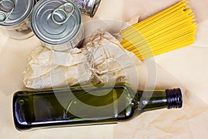 Tinned food, metal cans, olive oil bottle and yellow spaghetti pasta on light background. Grocery donation, charity and delivery