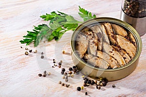 Tinned small smoked sardines on background with greens