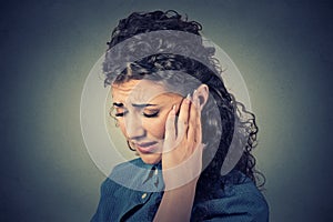 Tinnitus. Closeup sick female having ear pain touching painful head photo