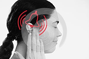 Tinnitus. A dissatisfied young woman holds her hand over her ears, experiencing ringing and pain. The concept of ear photo