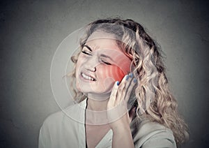 Tinnitus. Sick female having ear pain touching her painful head photo