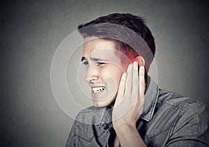 Tinnitus. Sick man having ear pain touching his painful head