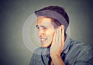 Tinnitus. Sick man having ear pain touching his painful head photo