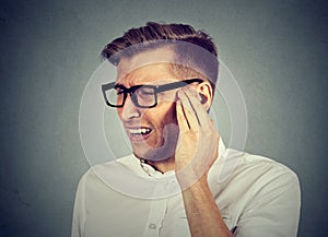 Tinnitus. Sick man having ear pain touching painful head photo