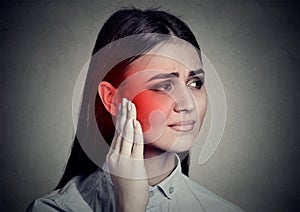 Tinnitus. Sick woman having ear pain touching her temple photo