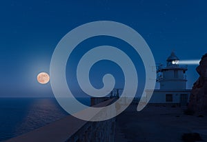The Tinoso lighthouse in Spain with the full moon over the sea. photo
