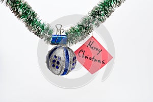 Tinsel with pinned christmas ornaments and paper with note Merry Christmas, white background. Merry Christmas concept