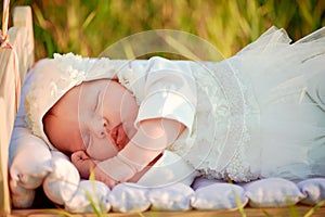 Tiny baby asleep in his crib in lace bonnet