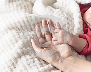 Tiny baby hand in her mother palm for love and protection concept