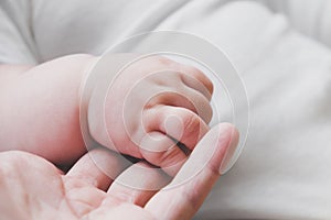Tiny baby hand holding mother`s finger. New life, togetherness and love concept.