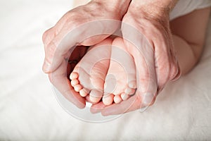 Tiny baby`s feet in male hand