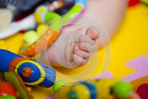 Tiny baby's foot among toys