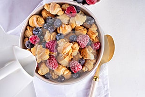 Tiny breakfast croissant cereals with fresh berries and milk