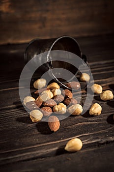 Tiny bucket of assorted nuts on a wooden background