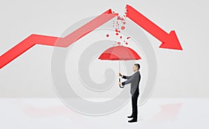 A tiny businessman hiding under a red umbrella from the rubble of a broken red statistic arrow.