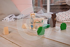 Tiny colorful wooden toy shapes and building blocks on hardwood floor.Girl play with a wooden set in their children`s