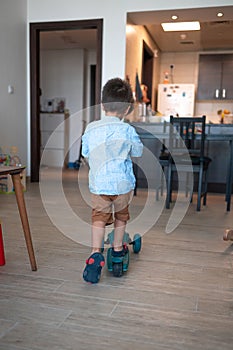 Tiny explorer: Cute toddler\'s blue push scooter adventures at home