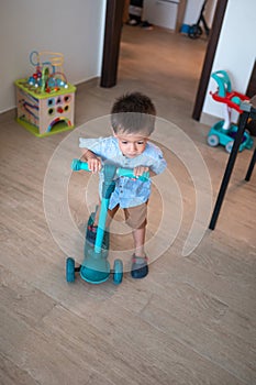 Tiny explorer: Cute toddler's blue push scooter adventures at home