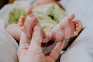 Tiny feet of newborn baby. Mother`s hand massaging baby feet. Maternity concept.