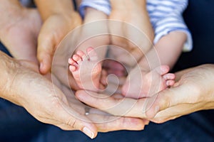 Tiny feet of newborn baby in it's parents' hands