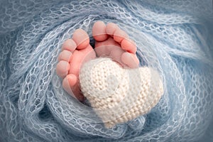 The tiny foot of a newborn baby. Soft feet of a new born in a blue wool blanket.