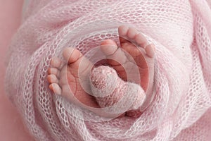 The tiny foot of a newborn baby. Soft feet of a new born in a pink wool blanket.