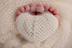 The tiny foot of a newborn baby. Soft feet of a new born in white blanket. Closeup of toes, heels and feet of a newborn.