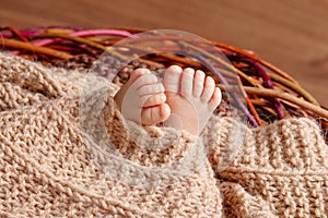 Tiny foot of newborn baby. Soft newborn baby feet against a beige  blanket. Baby feet with toes curled up