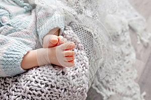 Tiny foot of newborn baby. Soft newborn baby feet against a beige  blanket. Baby feet with toes curled up. Copy space