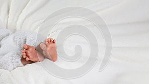 Tiny foot of newborn baby in soft selective focus, on a white textile background, the concept of a new life