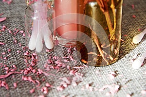 Tiny glass jar with cotton buds, pink lip gloss and scented flower petals