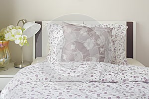 Tiny lavender pattern style bedding in bedroom with white orchid