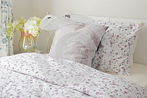 Tiny lavender pattern style bedding in bedroom with white orchid next to bed