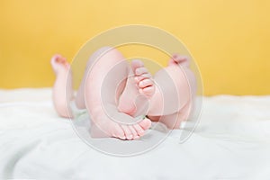 Tiny legs of a baby in a white bodysuit. An admiring innocent girl lying in a comfortable crib in the bedroom